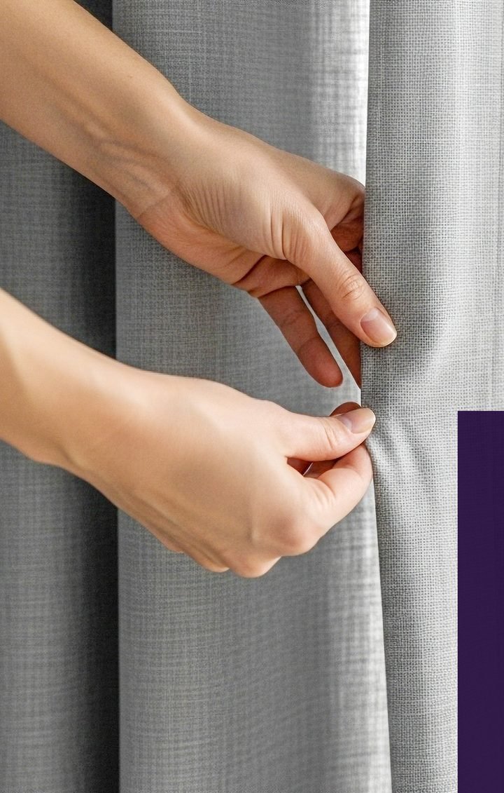 Hands styling a pinch-pleat curtain